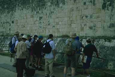 Group examining inscription on the side of the ballcourt